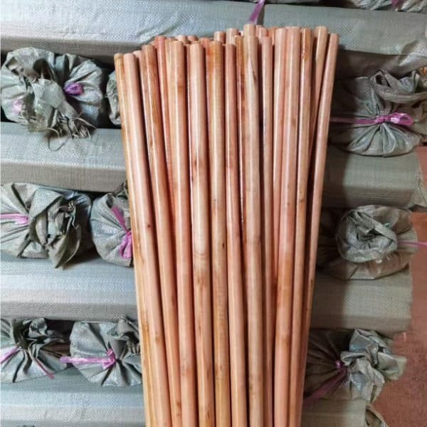Bundles of smooth varnished wooden broom handles neatly arranged against packaged goods, showcasing premium customized handle equipped garden broom factory products