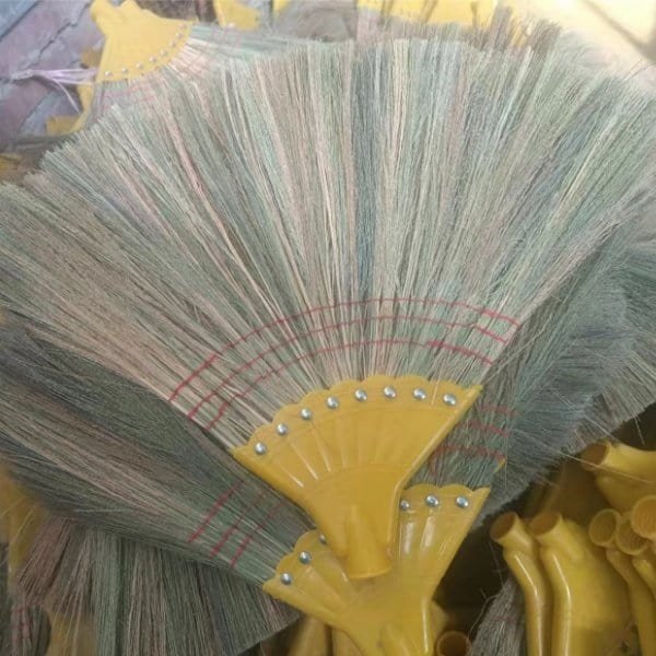 Natural fiber grass brooms with yellow plastic ferrules, made with materials from trusted grass broom raw material suppliers