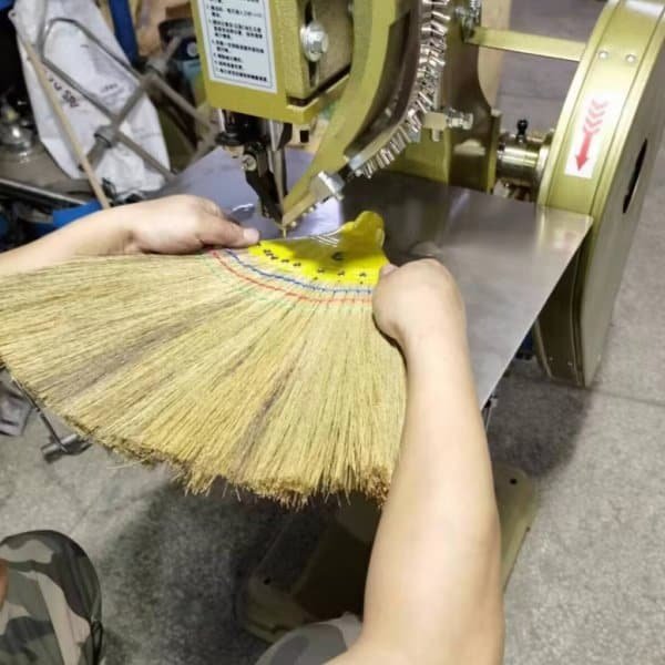 Worker assembling grass brooms on the production line, using materials from reliable grass broom raw material suppliers